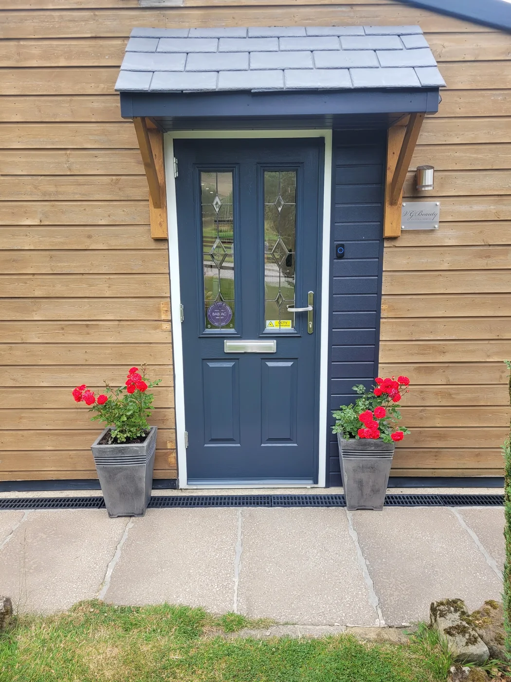 VGBeauty's wooden garden salon entrance with the salon name beside the door